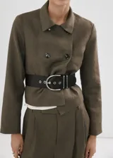 Chaqueta corta de lino color verde militar, de corte recto, con cuello alto camisero y cierre de doble botonadura.