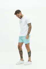 Short de baño liso con cintura elástica y cordón ajustable. Cuenta con dos bolsillos laterales, un bolsillo trasero y logo bordado en el ruedo. Confeccionado en tejido ligero de secado rápido.