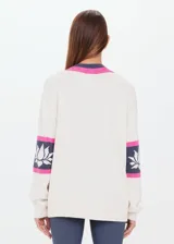 Sweater de punto color crema, con escote en pico con ribete rosa y gris. Presenta mangas largas con franjas grises y rosas en los puños, y logo bordado en el brazo.