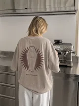 Remera oversize de color marrón topo con efecto acid wash, cuello redondo y manga corta. Cuenta con un pequeño estampado gráfico frontal con el texto 'WAKE UP IND' y una calavera.