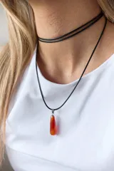 Gargantilla de cuero negro con dije de piedra blanca en forma de lágrima con engarce dorado.