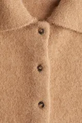 Cárdigan de punto suave color camel, con cuello camisero y cierre frontal de botones. Presenta hombros caídos y mangas amplias de corte tres cuartos. El bajo es de punto acanalado.