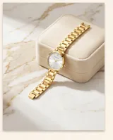 Reloj de pulsera analógico para mujer con caja y malla de eslabones en color dorado. Presenta una esfera minimalista de fondo claro con índices lineales y movimiento de cuarzo japonés.