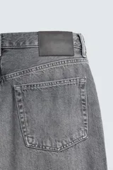Pantalón de jeans de algodón, color gris oscuro con efecto lavado. De tiro medio y corte relajado con pierna recta desde la cadera hasta el tobillo. Presenta cinco bolsillos y cierre frontal con botonadura.