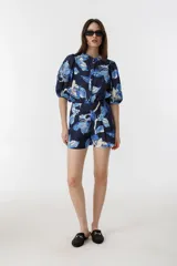 Short de tiro alto con estampado floral en tonos azules y blancos. Presenta pretina estructurada, pliegues frontales, bolsillos laterales y cierre frontal con ganchito interno metálico.