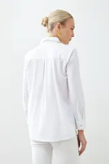 Camisa blanca de corte clásico, con cuello camisero, mangas largas con puños abotonados y cierre frontal con botones.