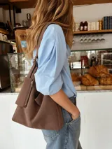Cartera tipo shopper de símil gamuza marrón, con correa de hombro ajustable y un neceser externo con cierre.