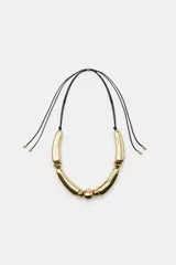 Collar de cordón negro con nudos y piezas metálicas doradas de diferentes formas y tamaños, con cierre ajustable mediante pieza circular.