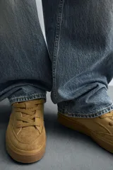 Zapatillas acordonadas color ocre, con suela de goma marrón con volumen.