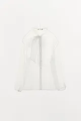 Camisa semitransparente de organza con cuello subido y lazada frontal del mismo tejido. Presenta manga larga con puños abotonados y cierre frontal con botones ocultos.