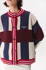 Cardigan de punto con diseño de bloques de color en tonos marrón, beige y verde. Presenta cuello redondo, cierre frontal con botones, mangas largas con hombros caídos y logo bordado en el frente.