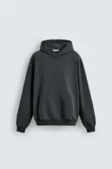 Sudadera tipo hoodie de corte relajado, color gris oscuro o negro lavado, con capucha, bolsillo canguro frontal y puños y bajo acanalados.