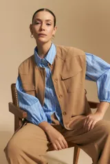 Camisa azul a rayas blancas, de manga larga con puños elastizados, entallada en la cintura y con cierre de botones frontales.