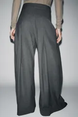 Pantalón de tiro medio con corte wide leg, confeccionado en tejido con viscosa y diseño de raya diplomática. Presenta pinzas frontales, bolsillos laterales ocultos y cierre frontal con cremallera, botón y ganchos metálicos.