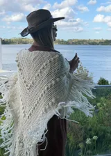 Ruana tejida artesanalmente en color crudo, con diseño triangular, textura de puntos en relieve y terminación con flecos largos en todo el borde.