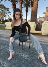 Bandolera negra de cuero con textura tipo cocodrilo en la solapa frontal, correa larga regulable y herrajes plateados.