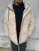Campera puffer impermeable color beige, con capucha desmontable forrada en corderito, cierre frontal con botones a presión y bolsillos laterales.