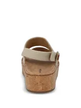 Sandalias de plataforma con suela de corcho. Presentan una tira frontal de cuero marrón y una tira superior de tela en color beige, con ajuste de hebilla metálica en el talón.
