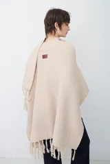 Ruana de tejido de punto en color negro, con diseño de cuello alto y terminaciones con flecos en los bordes.