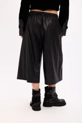 Bermuda sastrera de cuero sintético en color negro, con corte holgado y largo por debajo de la rodilla. Presenta cierre frontal con botón y bolsillos laterales.