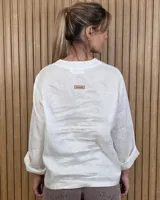 Blusón de lino blanco con cuello en V y mangas largas con vuelta.