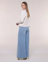 Camperita corta blanca de punto elastizado, con cuello camisero, cierre frontal completo y mangas largas con puños anchos abotonados.