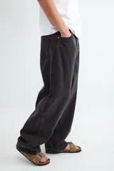 Jean de corte holgado y tiro medio, confeccionado en denim de algodón con lavado gris oscuro y efecto desgastado. Presenta diseño de cinco bolsillos, cierre frontal con botón y etiqueta de cuero en la parte posterior.
