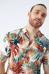 Camisa de manga corta con estampado botánico de hojas en tonos azul y blanco. Presenta cuello clásico, cierre frontal abotonado y corte slim.