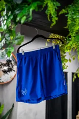 Short deportivo azul con cintura elástica, bolsillos laterales y logo estampado en la pierna izquierda.
