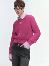 Cárdigan de tejido de punto grueso en color fucsia, con cuello redondo, cierre frontal de botones dorados y puños acanalados.