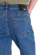 Jeans de corte slim en denim azul con efecto lavado, cierre de cremallera y botón, diseño de cinco bolsillos y detalles de la marca CAT.