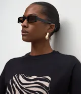 Remera de algodón color negro con cuello redondo y mangas cortas. Presenta una estampa frontal abstracta con líneas onduladas en tonos claros.