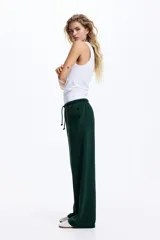 Pantalón tipo jogger de corte holgado y piernas amplias, confeccionado en felpa con interior cepillado. Presenta cintura elástica con cordón de ajuste y bolsillos laterales discretos.