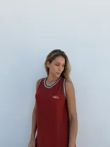 Vestido midi de punto acanalado color ladrillo, corte recto y sin mangas, con cuello redondo ribeteado en blanco y logo bordado en el pecho.