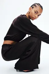 Pantalón marrón oscuro de corte holgado y piernas amplias, con cintura elástica fruncida y cordón ajustable.