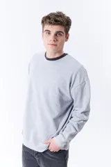 Buzo deportivo gris melange de corte clásico con cuello redondo y mangas largas.