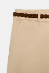Pantalón chino beige de tiro bajo, con pernera recta y bajo con vuelta. Incluye bolsillos delanteros, falsos bolsillos traseros con solapa y cierre frontal con cremallera y botón. Viene acompañado de un cinturón trenzado marrón.