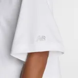 Remera blanca de corte cuadrado y holgado, con cuello redondo y mangas cortas. Presenta un estampado frontal con diseño de flores en estilo acuarela y el logo de la marca en el centro.