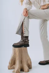 Botas de caña media color negro, confeccionadas en cuero natural, con suela track y plataforma alta. Cuentan con múltiples correas con hebillas metálicas plateadas y tachas decorativas.
