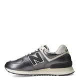 Championes urbanos New Balance modelo 574, color gris metalizado con detalles en crema y blanco. Presentan el logo N característico en los laterales, cordones al tono y suela con tecnología de amortiguación.
