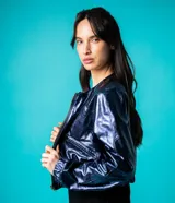 Bomber azul marino de cuero con mangas ranglán, bolsillos laterales, elástico en la cintura y cierre metálico delantero.