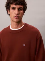 Sweater Calvin Klein de corte relajado, color marrón, con cuello redondo, puños y bajo acanalados, y pequeño monograma CK bordado en el pecho.