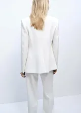Chaqueta tipo americana de diseño estructurado y corte recto, color blanco. Presenta cuello con solapas de muesca, cierre frontal con un botón, mangas largas con puños abotonados y dos bolsillos de parche frontales. Incluye forro interior.