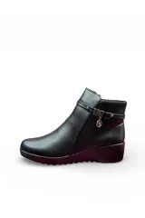 Bota corta de cuero color negro, con taco cuña y detalle de tira decorativa con aplique metálico en el lateral.