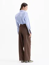 Pantalon de corte ancho y tiro alto, color marron, confeccionado en poplin elastizado. Presenta tablas en la cintura que aportan volumen, cierre frontal y un lazo ajustable con argollas metalicas.