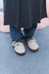 Pantuflas marrones con interior de corderito color crema y ajuste con velcro.