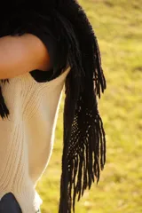 Bufandón triangular tejido en lana merino, con diseño calado y terminaciones con flecos largos en los extremos. Versátil para usar como bufanda o chal.