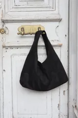 Cartera tipo hobo de gamuza negra, con diseño minimalista y asa integrada.