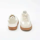 Zapatillas deportivas bajas de estilo retro, color blanco con detalles en tono crema y suela de goma color caramelo. Presentan cierre con cordones y puntera reforzada con diseño dentado.