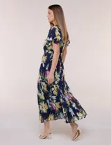 Vestido midi azul marino con estampado floral multicolor, confeccionado en gasa liviana con falda plisada. Tiene escote en V, mangas cortas estilo mariposa y lazo ajustable en la cintura.